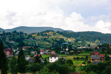 Ukrainian village in the Carpathian mountains in sunny evening. Beautiful landscape during the evening light. Country side view of vertex in the middle of summer. Rural landscape with forest. Hills.