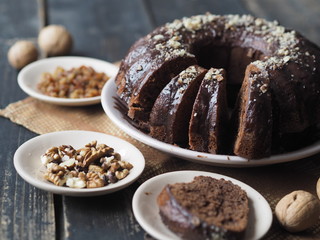 Festive homemade cakes. Round chocolate muffin, large sponge cake or cake with chocolate icing on a dark wooden background. Place for text, side view.
