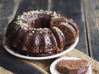 Festive homemade cakes. Round chocolate muffin, large sponge cake or cake with chocolate icing on a dark wooden background. Place for text, side view.