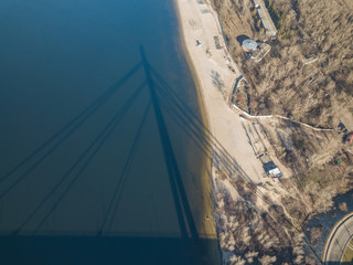 Aerial drone view. The shadow of the North Bridge in Kiev falls on the sandy shore and water.