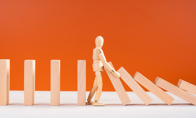 Wooden man stopping falling domino concept. Symbol of crisis, risk, management, leadership and...
