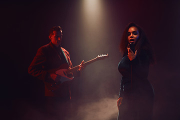 A jazz singer and guitarist perform on stage.