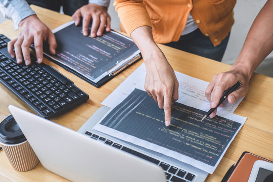 Two professional programmer cooperating and working on web site project in a software developing on desktop computer at company, codes and typing data code, Programming with HTML, PHP and javascript