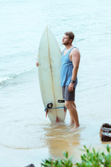 Naklejka premium Man with surfboard on the beach. Surfer in Sri Lanka Mirissa. Blue wave