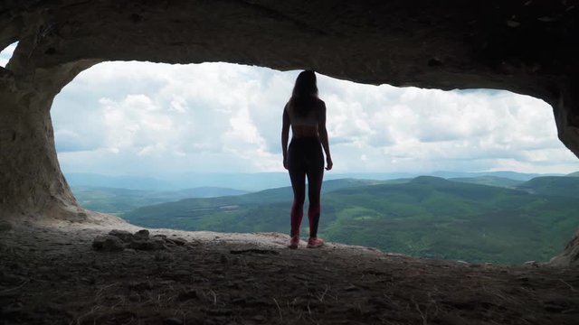 Girl traveler walks through the cavern. Cave city in the vicinity of Bakhchisarai - tope kermen. Attractions in Crimea. Slow motion. Shooting on the Steadicam