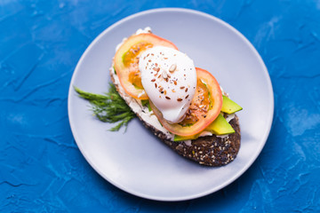 Sandwich with smoked salmon, egg and avocado on blue background, top view. Concept for healthy nutrition.