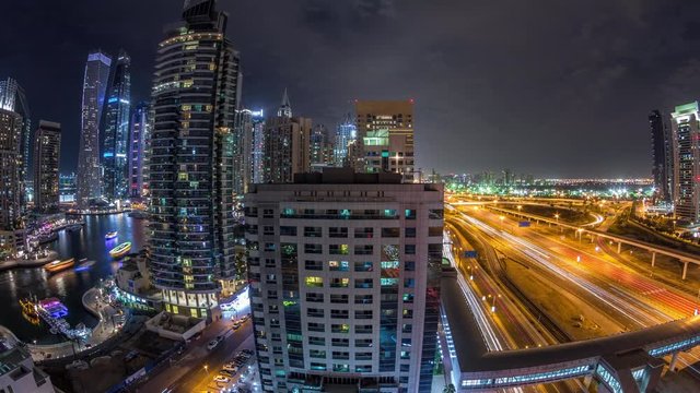 Aerial panoramic view to Dubai Marina skyscrapers and Sheikh Zayed road night timelapse, Dubai. Traffic, bridges and metro line. United Arab Emirates