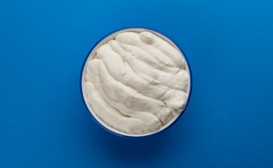 Bowl of sour cream on blue background