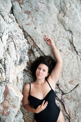 Top view model size plus in black swimming suit on the cliffs. Body Positive concept