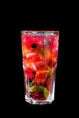 A single-colored, red cocktail in a tall glass with fine ice and lemon, lime and mint leaves. Side view. Isolated black background. Drink in a glass glass for the menu restaurant, bar, cafe