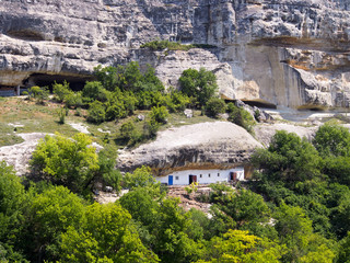 Fototapeta na wymiar The house is built in a rock, white facade against a background of brown rocks and dense vegetation. Travel in the mountains, the concept of active recreation.