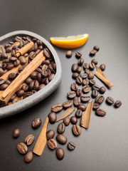 Scattered coffee beans and coffee beans with cinnamon on a black background.