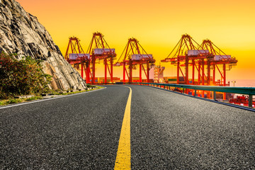 Fototapeta na wymiar Empty asphalt highway and industrial container terminal at beautiful sunset in Shanghai.
