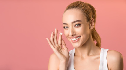Obraz na płótnie Canvas Happy Woman Applying Facial Cream Standing On Pink Background, Panorama
