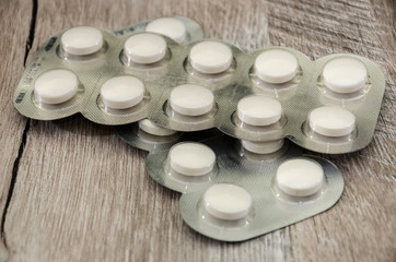 white pills on a wooden table. Close-up.