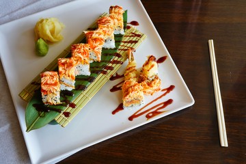 A plate of fried shrimp tempura and spicy crab sushi roll with eel sauce at a Japanese restaurant