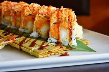 A plate of fried shrimp tempura and spicy crab sushi roll with eel sauce at a Japanese restaurant