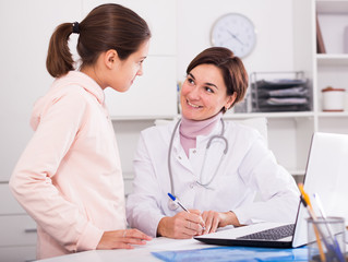 Doctor fills patient card for girl