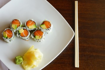 A plate of avocado and salmon sushi roll with pickled ginger and wasabi at a Japanese restaurant