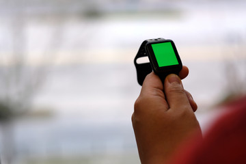 over shoulder of one person holding green screen smart watch. blur background