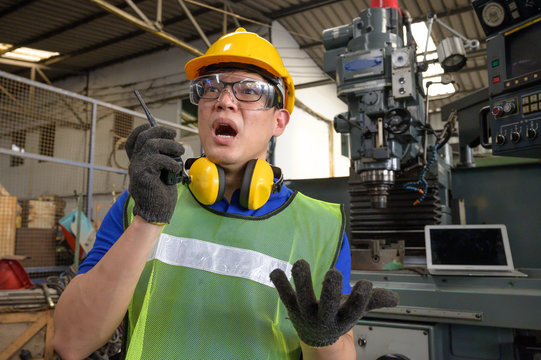 Asian male inspector, engineer shocking and commanding with walkie-talkie in hand