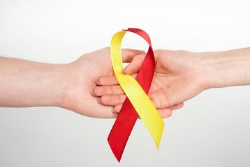 cropped view of man and woman holding red and yellow ribbon as hepatitis c awareness isolated on white