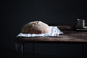 Appetitliches Bio Sauerteig Brot auf einem Leintuch auf  Holztisch vor dunkelem Hintergrund