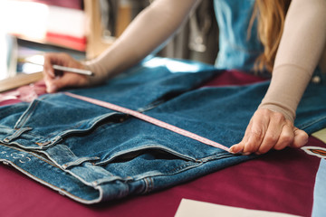 Cropped photo of mature woman seamstress measuring jeans