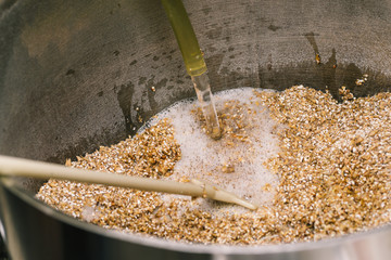 Brewing beer. Stirring the malt with a long stirrer. Water is sprayed into the malt tank. The technology of making beer. - obrazy, fototapety, plakaty