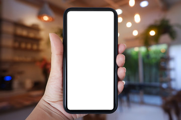 Close-up hand holding phone vertical, Using smart phone with blurred background of house, cafe interior - copy space