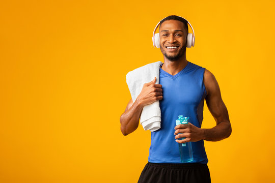 Healthy afro sports guy holding bottle of mineral water