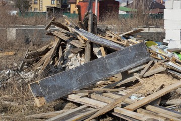gray and brown wooden boards in a heap of garbage outdoors on a sunny day