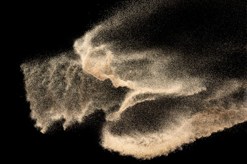 Brown colored sand splash.Dry river sand explosion isolated on black background. Abstract sand...