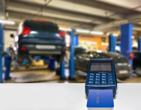 Car service payment of car repair card with the payment terminal. All silhouettes of cars are distorted for unrecognizability.