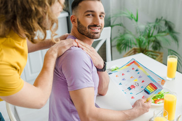 happy homosexual men holding hands near picture with lgbt flag