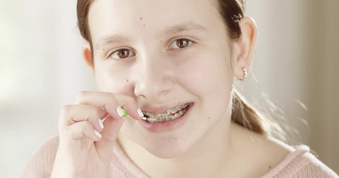 Pretty Little Girl Using Interdental Brush to Clean Her Teeth Braces while Looking at Camera Mirror Smiling a Dental Orthodontist Health Care Concept 