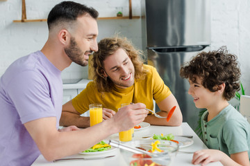 happy homosexual man feeding mixed race son
