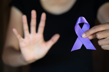 Purple ribbon in a woman's hand, Domestic Violence Awareness Month (October) concept with deep...