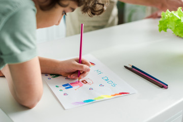 selective focus of mixed race kid drawing picture with my dads lettering