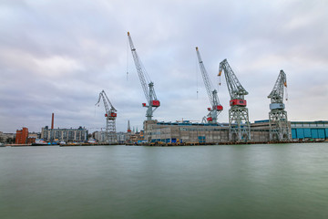 Fototapeta premium City working area, cargo port with cranes on the seashore. Helsinki panorama, Finland - February 18, 2020: Lautasaari island in cloudy weather. Early morning.
