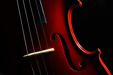 Detalle de violín con enfoque selectivo y fondo oscuro en clave baja.