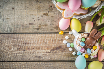 Easter hot chocolate with chocolate bunny rabbits. easter eggs and marshmallow, wooden background with spring flowers copy space