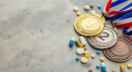 Doping for athletes. Gold, silver and bronze medal and pills with capsules on a gray background