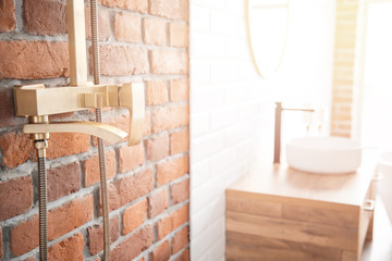 Modern shower system copper color for bathroom in loft style, brick wall. Sunlight window