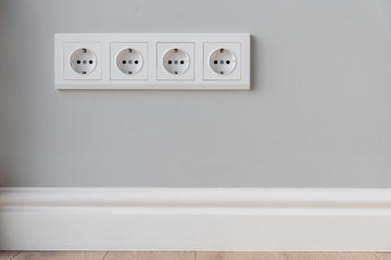 White European sockets on gray concrete wall in loft style, with high polyurethane baseboard