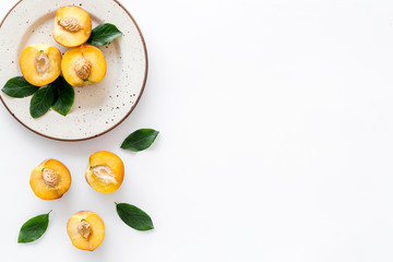 Healthy food. Ripe sliced peaches on plate on white table top-down copy space