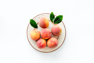 Naklejka na ściany i meble Summer fruits. Ripe red peaches on plate on white table top-down copy space