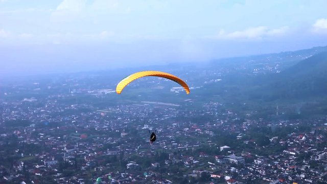 Footage of single paraglider in the sky with yellow parachute