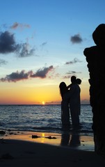 Golden silhouette of a couple at sunset reflected in the waters