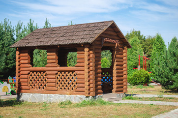 Wooden gazebo made of logs on the summer courtyard